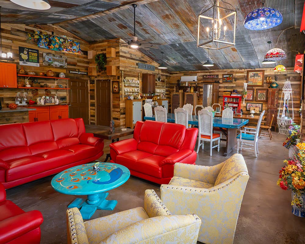 A cozy and colorful living space featuring red couches, a turquoise coffee table, and rustic wooden decor.