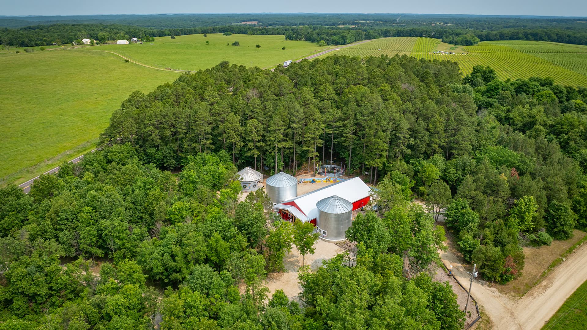 Aerial view of a rural farm surrounded by trees and fields.