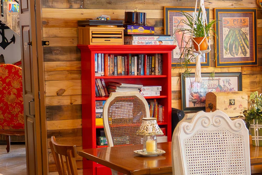 A cozy interior featuring a red bookshelf, dining table, and wall art in a wooden setting.