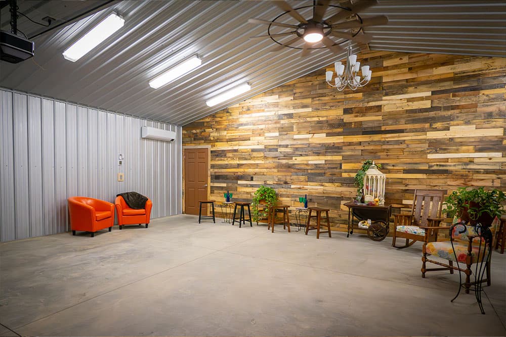 A spacious interior featuring orange chairs, wooden accents, and various plants against a rustic wall.