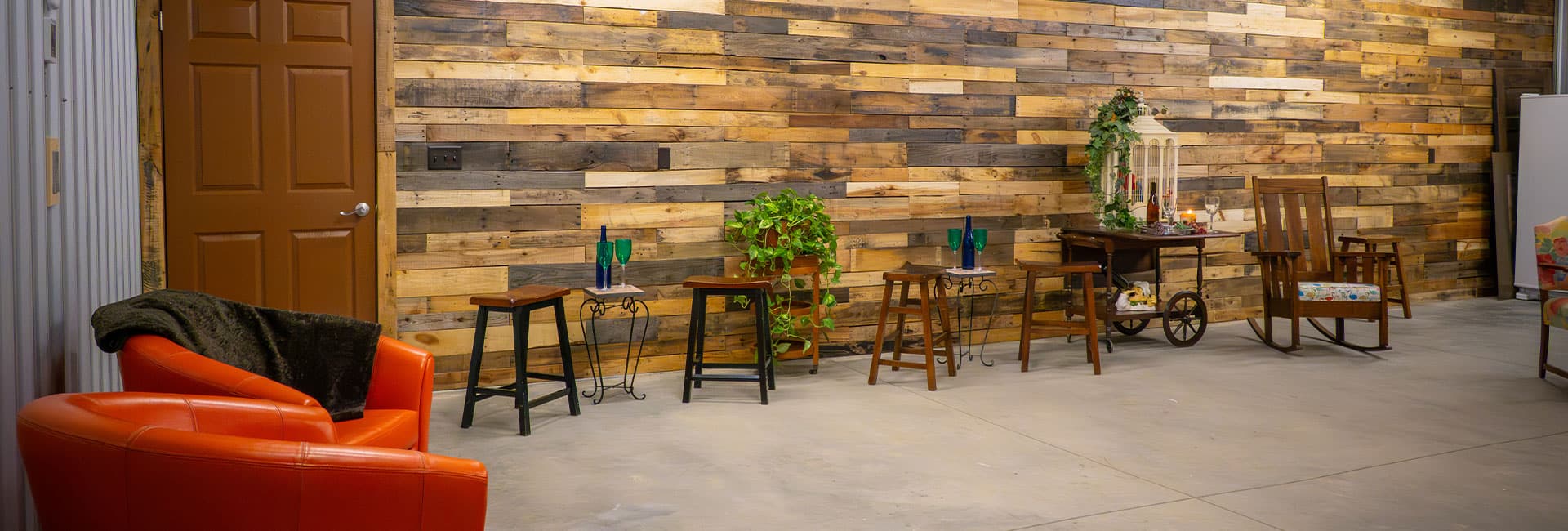 A cozy indoor space with a rustic wooden wall, accompanying furniture, and an orange chair.