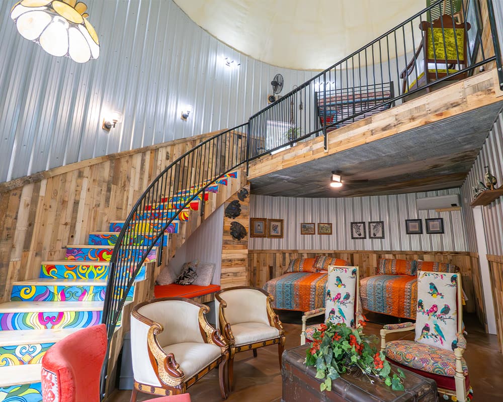 A vibrant interior featuring a spiral staircase, colorful decor, and cozy seating arrangements.